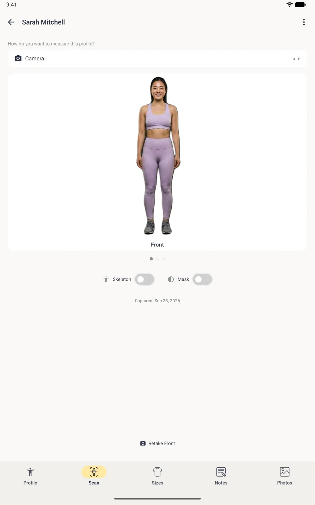 A full-screen Scan tab on a tablet with Camera chosen in the mode dropdown, showing a front-facing photo of a woman in lilac activewear with the background removed and labelled Front, three page dots, Skeleton and Mask switches both off, a Captured date and, far below, a Retake Front link above the profile tab bar.