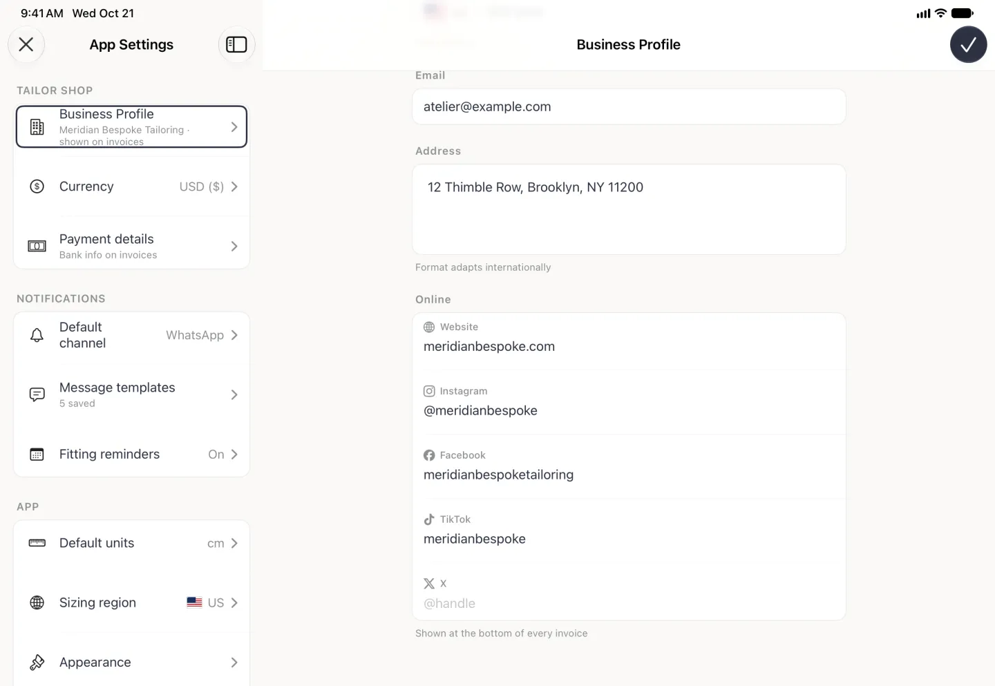 App Settings split view with Business Profile outlined in the list on the left, and the Business Profile page on the right scrolled to its end under the checkmark button: the filled Email field, Address 12 Thimble Row, Brooklyn, NY 11200 with the note Format adapts internationally, then the Online card listing Website meridianbespoke.com, Instagram @meridianbespoke, Facebook meridianbespoketailoring, TikTok meridianbespoke and an empty X field with the placeholder @handle, each label beside its platform logo, above the note Shown at the bottom of every invoice.