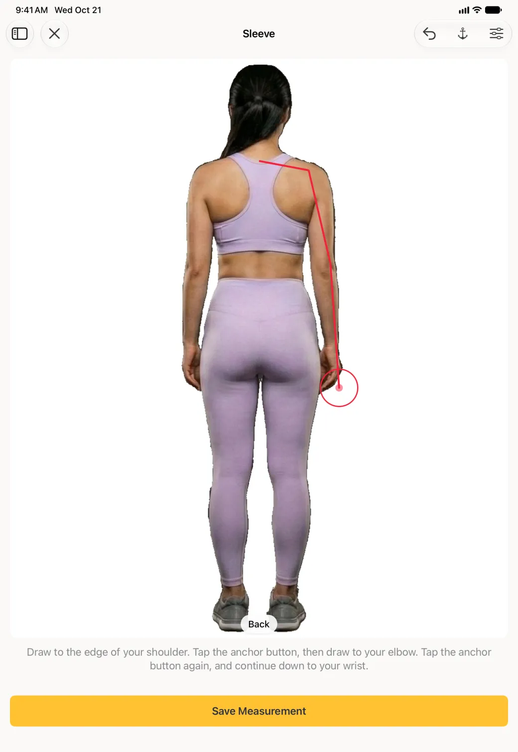 A large back view scan photo on the iPad with a red line running from the base of the neck out to the shoulder, then bending down the outside of the arm past the elbow to the wrist, with the red target circle at the wrist, the anchor instructions below the photo and a wide yellow Save Measurement button; undo, anchor and sliders buttons sit at the top right.