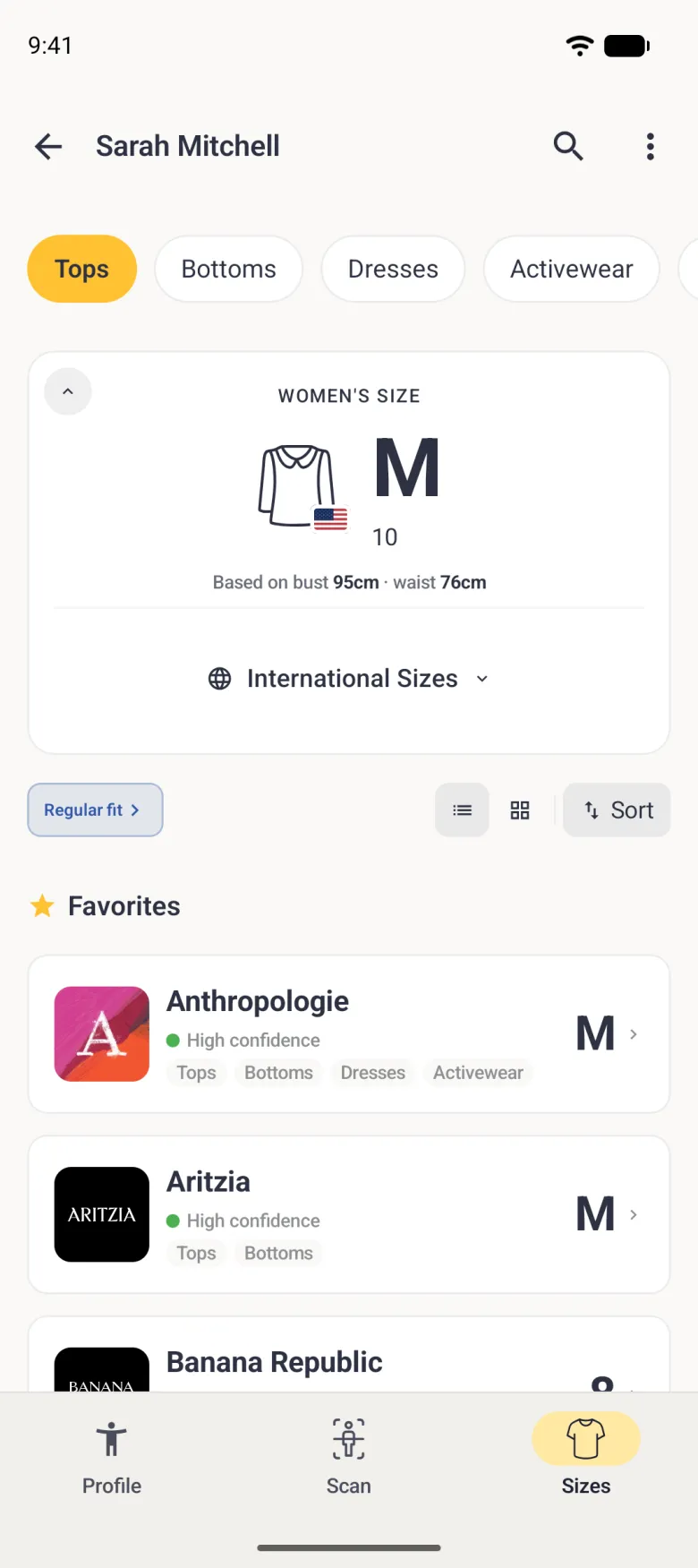A Sizes tab for Sarah Mitchell with the Tops chip selected in a row of category chips that continues off the right edge, a card reading Women's Size M with 10 underneath and a small US flag on the shirt icon, based on bust 95cm and waist 76cm, a folded International Sizes row, a Regular fit pill with list, grid and Sort buttons, and a Favorites list with Anthropologie (M) and Aritzia (M), each with a green High confidence dot and category tags, and Banana Republic starting below them.