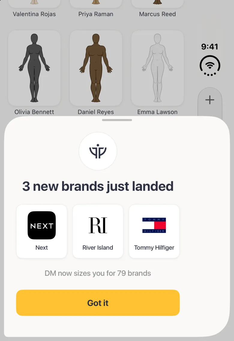 A sheet with a grabber over the lower half of the dimmed Clients grid on the closed Duo, titled 3 new brands just landed, with the DM mark at the top, three logo cards side by side for Next, River Island and Tommy Hilfiger, the line DM now sizes you for 79 brands and a gold Got it button; the sheet spans the full width, over the vertical bar strip.