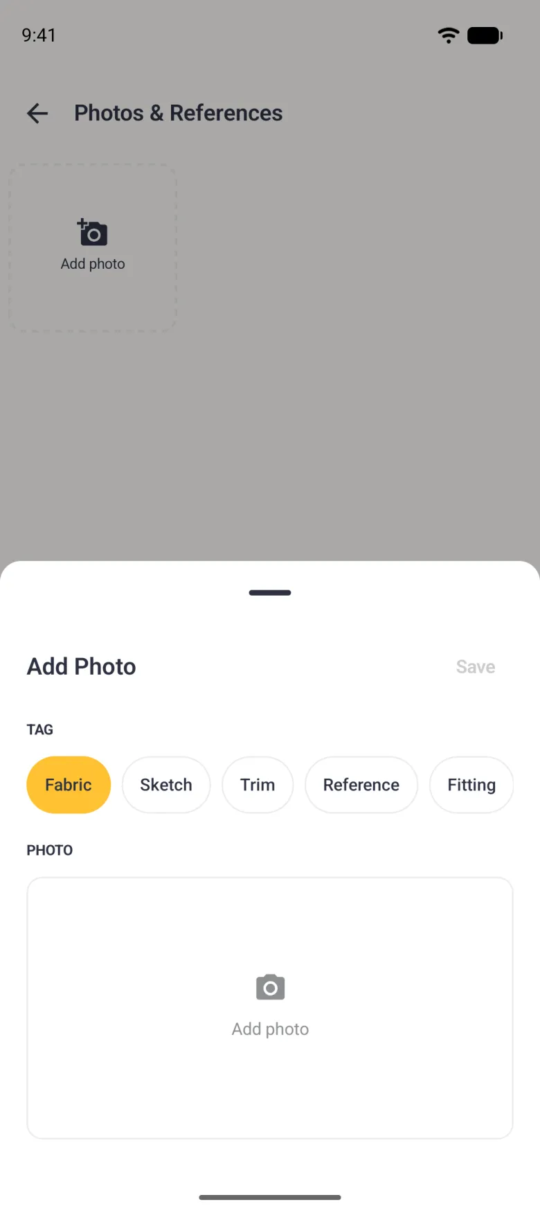 Add Photo sheet over the dimmed Photos & References screen, with a grey Save at the top right, tag chips reading Fabric, Sketch, Trim, Reference and Fitting with Fabric selected in gold, and an empty Add photo area below.