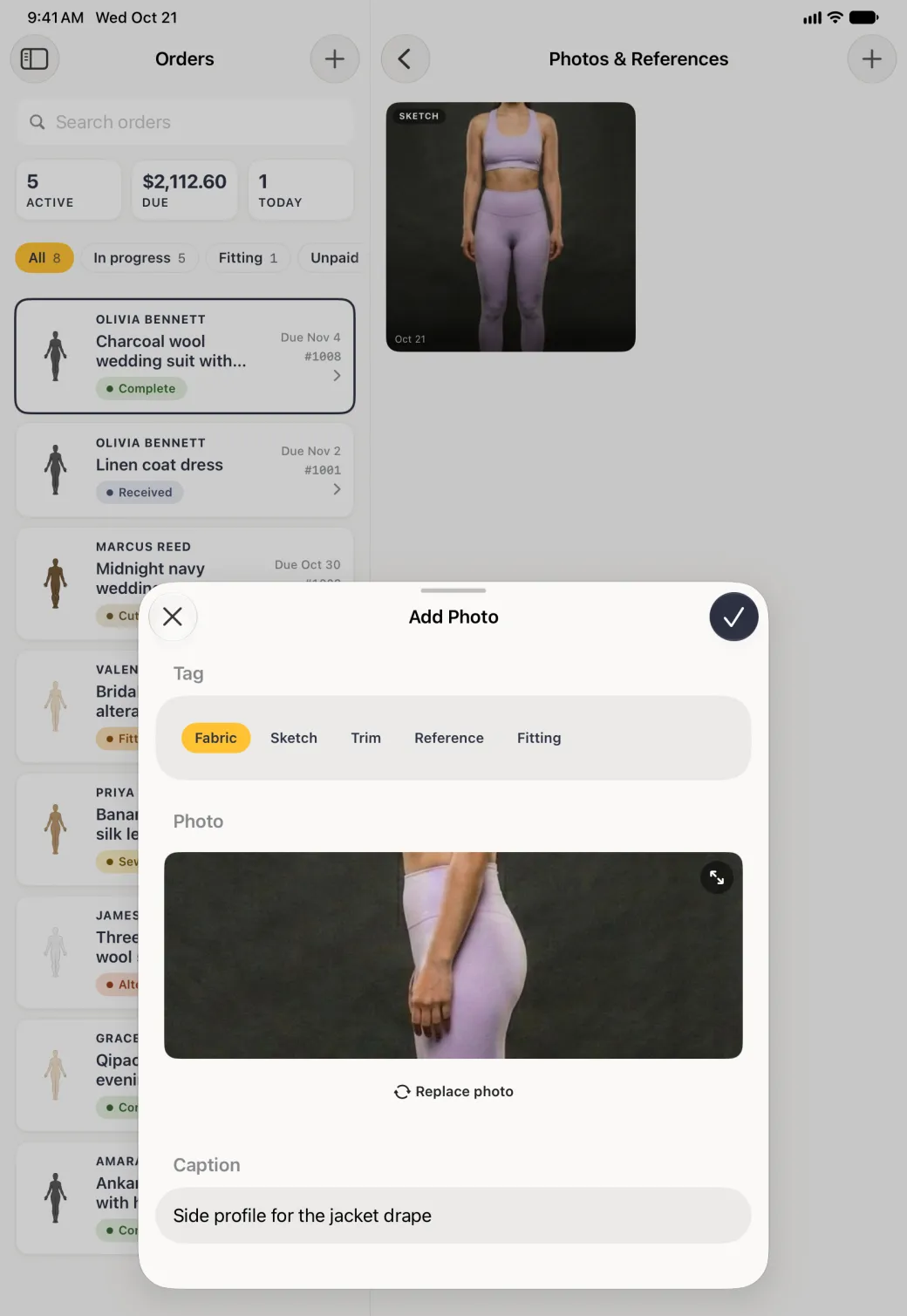 Add Photo sheet over the dimmed Orders list and the Photos and References pane with its Sketch photo, with the Fabric tag selected, a side-profile body photo filling the preview with an expand button in its corner, a Replace photo link below it, a caption reading Side profile for the jacket drape, and the round navy tick at the top right now solid.