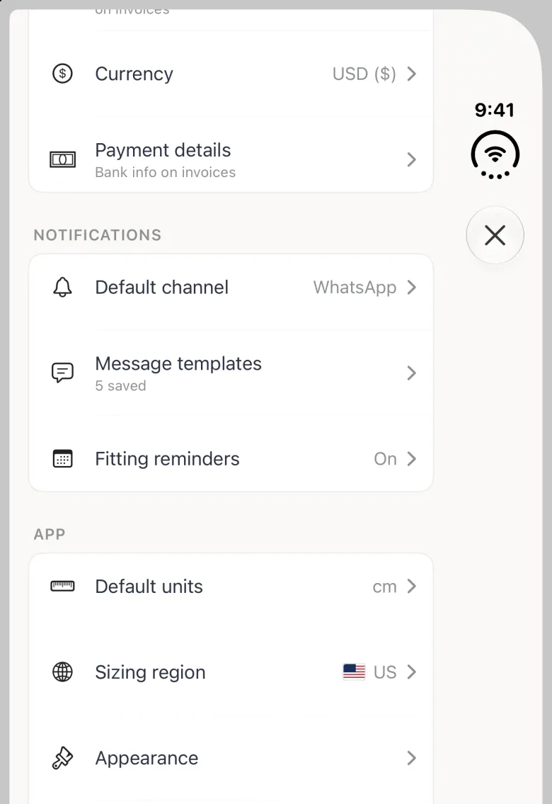 App Settings sheet on the closed iPhone Duo, scrolled a little, with its close button (a cross) in the vertical bar strip on the right edge. Currency USD ($) and Payment details close the Tailor Shop group at the top; the Notifications group lists Default channel set to WhatsApp, Message templates with 5 saved underneath, and Fitting reminders reading On. The App group starts below with Default units cm, Sizing region US and Appearance.
